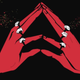 Two red hands wearing rings, tented together against a black background